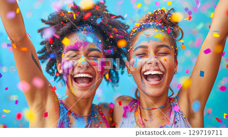 Joyful young women celebrating with colorful confetti and vibrant face paint in a festive atmosphere 129719711