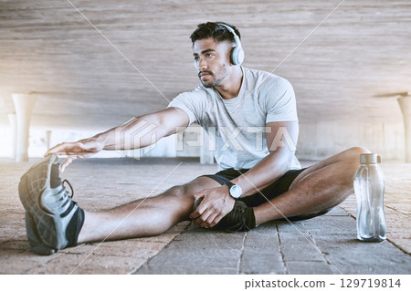 Sports, training and running stretching of a fitness trainer or runner about to start a workout. Running man athlete with headphones ready to improve health, wellness and performance with a exercise Sports, training and running stretching of a fitness trainer or runner about to start a workout. Running man athlete with headphones ready to improve health, wellness and performance with a exercise 129719814