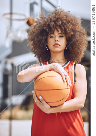 Portrait of a basketball player woman on a court holding a ball outdoors and ready for a sports competition. Trendy and serious African American woman athlete with cool wellness style or fashion Portrait of a basketball player woman on a court holding a ball outdoors and ready for a sports competition. Trendy and serious African American woman athlete with cool wellness style or fashion 129719861