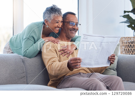 Love, senior couple and reading newspaper, story or news article in living room home. Retirement, relax time and happy elderly man and woman embrace in house, hugging or cuddle together and bonding. 129720086