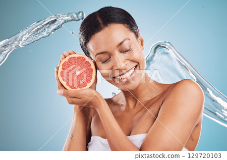 Grapefruit, black woman and water for skincare, cosmetics and hygiene with blue studio background. Citrus, young female and girl with smile, body care or natural beauty to relax, smooth or clear skin 129720103