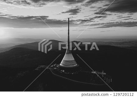 As the sun sets over Jested Mountain Hotel in Liberec, the modern architecture contrasts beautifully with the evening sky, showcasing the famous TV transmitter and scenic landscape. 129720112
