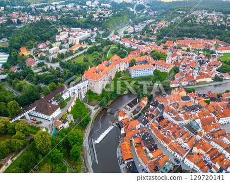 The captivating town of Cesky Krumlov is bathed in morning light, showcasing its iconic castle, colorful rooftops, and the winding Vltava River. 129720141