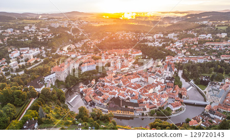 The sunrise casts golden hues over Cesky Krumlov, illuminating the historic town and its castle. Nestled along the Vltava River, the city's stunning architecture reflects a rich heritage. 129720143