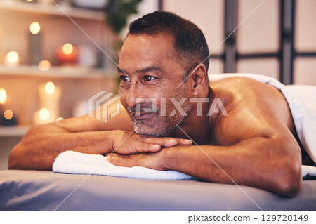 Man, spa massage and table to relax for zen, calm and physical therapy while on vacation for happiness, health and wellness. Face of male thinking about body treatment at beauty salon with a smile 129720149