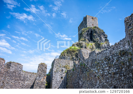 Trosky Castle Ruins rise dramatically in the Bohemian Paradise region of Czechia. Visitors can admire the ancient stone walls and panoramic views on a sunny day with blue skies. 129720166