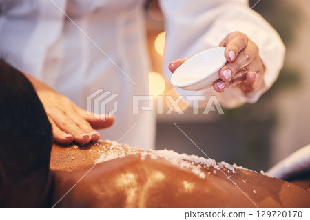 Massage, spa and scrub on a back for exfoliate treatment for soft, healthy and smooth skin. Luxury, wellness and therapist doing salt body exfoliation detox for health, hygiene and body care at salon 129720170