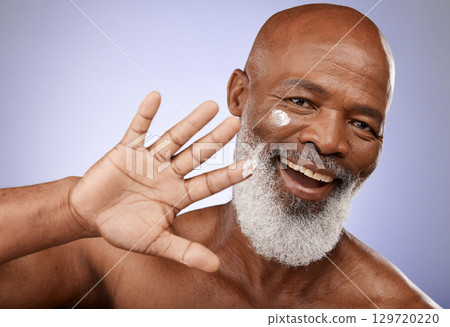 Skincare, cream and senior black man in studio beauty, cosmetics or face product promotion, marketing or advertising. Happy portrait of elderly model with facial, sunscreen or dermatology application 129720220