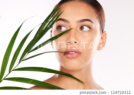 Leaf, beauty and woman with heatlhy skincare, natural cosmetics and wellness, glow and sustainability on studio background. Beautiful model face, green leaves from plants and eco friendly dermatology 129720312