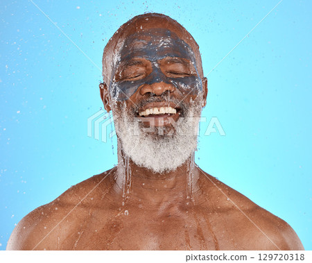 Skincare, water and black man with mask for facial on blue background in studio for wellness, spa and cleanse. Dermatology, cleaning and senior male with face mask, skin treatment and water splash 129720318