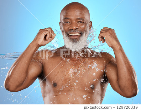 Man, splash and skincare for wellness in studio with smile, happiness and self care by blue background. Senior black man, model and cosmetics for health, moisturizer or face glow by studio background 129720339