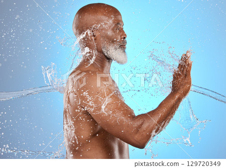 Black man, skincare and water splash for beauty, cosmetics and dermatology on blue studio background for old age skin and body. Model cleaning, washing and shower for hygiene, health and wellness Black man, skincare and water splash for beauty, cosmetics and dermatology on blue studio background for old age skin and body. Model cleaning, washing and shower for hygiene, health and wellness 129720349