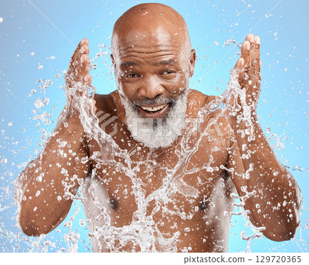 Black man cleaning face, water splash and skincare with beauty, hygiene and facial care in portrait against blue background. Mature model with water, splash and skin hydration, wellness and grooming. Black man cleaning face, water splash and skincare with beauty, hygiene and facial care in portrait against blue background. Mature model with water, splash and skin hydration, wellness and grooming. 129720365