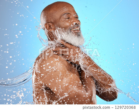 Beauty, water and cleaning splash of senior man for body care, hygiene and health lifestyle. Happy, shower and mature black model washing skin at studio blue background with satisfied smile. 129720368