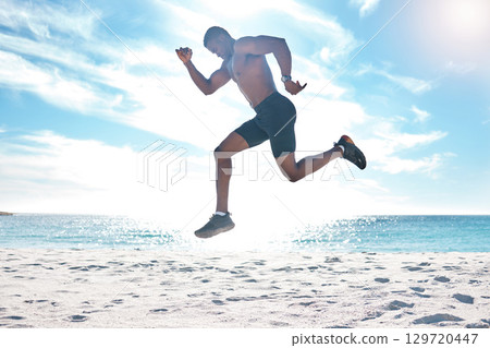 Fitness, runner and jump of black man at beach for cardio workout, training and wellness body. Summer, run and focus of strong athlete running and jumping on sand at ocean in Los Angeles, USA. Fitness, runner and jump of black man at beach for cardio workout, training and wellness body. Summer, run and focus of strong athlete running and jumping on sand at ocean in Los Angeles, USA. 129720447