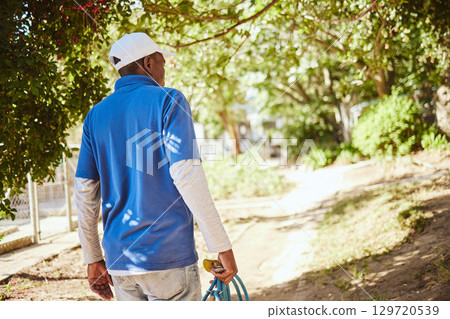 Outdoor animal shelter, cleaning and worker with hose walking in nature to clean for volunteer work. Community, charity and black man working at rescue center for dogs, animals and adoption of pets 129720539