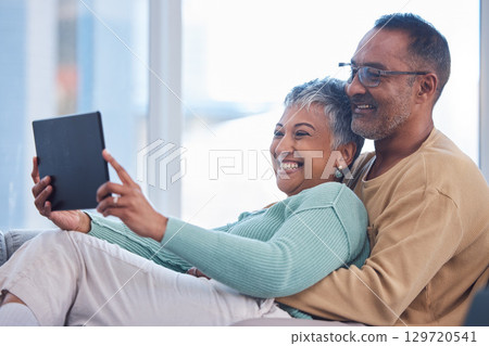 Movie, communication and senior couple with a tablet, streaming film and show on the living room sofa of their house. Website, social media and elderly man and woman with comedy and app on tech 129720541