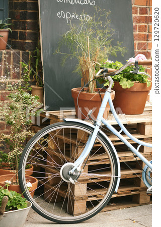 Bicycle, cafe and small business outdoor restaurant or coffee shop for background in Paris with decoration, plants and menu board. Bike, carbon footprint and street, terrace or patio with wheel 129720620