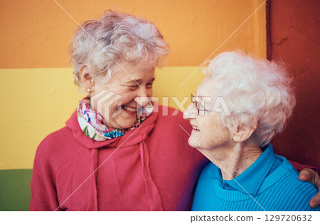 Friends, happy and retirement with a senior woman and friend outdoor together on a color wall background. Smile, freedom and glasses with mature female friendship bonding or laughing outside Friends, happy and retirement with a senior woman and friend outdoor together on a color wall background. Smile, freedom and glasses with mature female friendship bonding or laughing outside 129720632