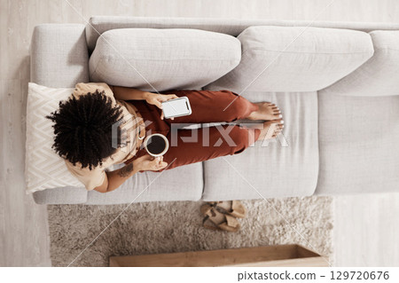 Top view, relax and black woman with phone on sofa drinking coffee and on social media, internet and online. Communication, technology and girl with mockup screen on smartphone for mobile app at home Top view, relax and black woman with phone on sofa drinking coffee and on social media, internet and online. Communication, technology and girl with mockup screen on smartphone for mobile app at home 129720676