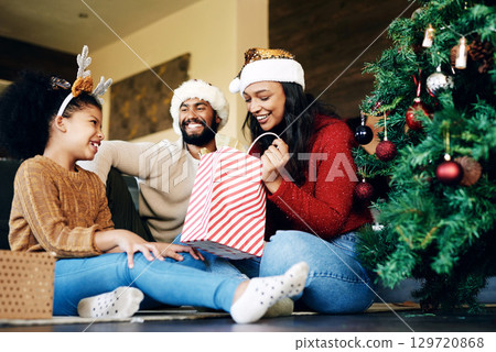 Christmas, love and family opening gifts in home, having fun and bonding on holiday. Xmas spirit, care and happy father, mother and girl exchange presents in living room and enjoying quality time. 129720868