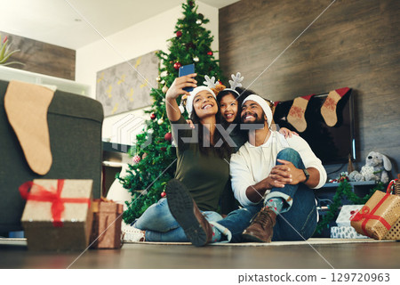 Family, selfie and celebrating christmas with a man, woman and child excited in a family photo for the festive season. Xmas, gift and mobile picture for social media with parents and kids 129720963