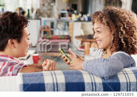 Friends, happy and phone of a woman listening to music in a friend conversation at a party. Podcast, internet radio and social media app of a person with happiness and smile talking on a sofa Friends, happy and phone of a woman listening to music in a friend conversation at a party. Podcast, internet radio and social media app of a person with happiness and smile talking on a sofa 129721055