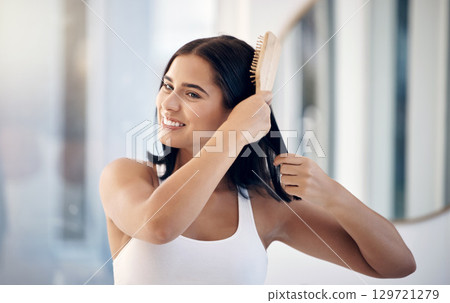 Hair, brush and bathroom with a woman in her home, brushing her hairstyle for haircare or treatment. Mirror, wellness and luxury with a female using cosmetic shampoo or keratin on her head in a house 129721279