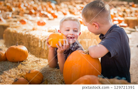 Two Boys Having Fun at the Pumpkin Patch on a Sunny Fall Day. 129721391