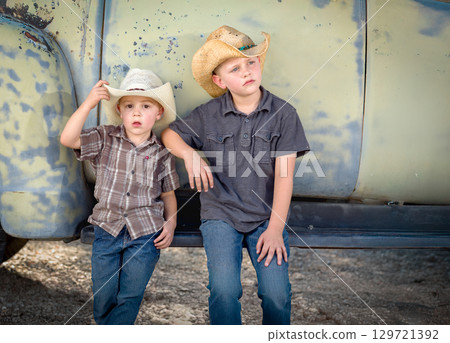 Two Young Boys Wearing Cowboy Hats Leaning Against Antique Truck 129721392