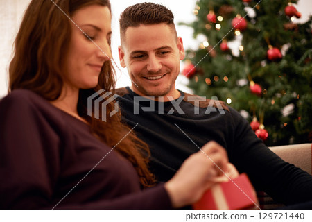 Gift, christmas and couple relax together for holiday festive celebration. Happy, smile and surprise present box to celebrate xmas, love and happiness on sofa in living room with christmas tree Gift, christmas and couple relax together for holiday festive celebration. Happy, smile and surprise present box to celebrate xmas, love and happiness on sofa in living room with christmas tree 129721440