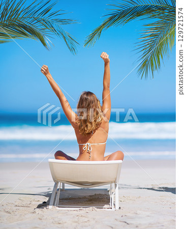 Beach, relax and back view of woman on chair on vacation, holiday or summer trip. Freedom, peace or young female in bikini stretching at seashore, enjoying ocean view or having fun on tropical island Beach, relax and back view of woman on chair on vacation, holiday or summer trip. Freedom, peace or young female in bikini stretching at seashore, enjoying ocean view or having fun on tropical island 129721574
