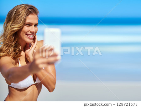 Influencer, phone and woman taking a selfie at a beach for a social media audience or travel blog online in Sao Paulo, Brazil. Model, content creator or happy girl taking pictures in summer in bikini 129721575