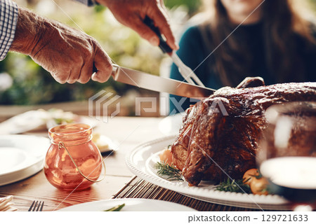 Turkey, thanksgiving and chicken cut by hands at a table for a family at a home or house gathering celebration. Party, zoom and man with knife cutting food or meat to celebrate and eat with friends 129721633