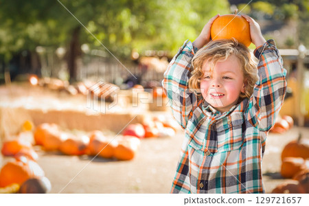 Cute Young Boy Having Fun at the Pumpkin Patch on a Sunny Fall Day. 129721657