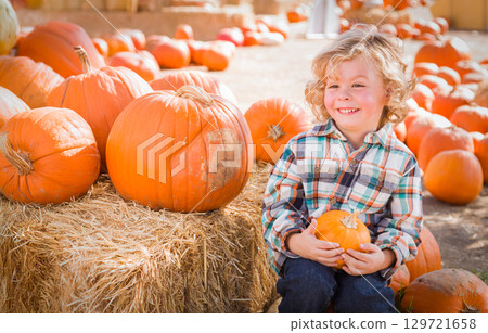 Cute Young Boy Having Fun at the Pumpkin Patch on a Sunny Fall Day. 129721658