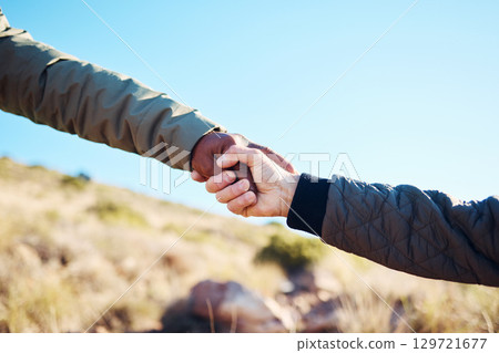 Friendship, help and men holding hands on a hike for support while climbing a rock on a mountain. Assistance, adventure and interracial male friends trekking together for fitness challenge in nature. 129721677