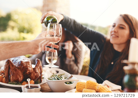 Party, dinner and woman pouring wine in a wine glass to cheers at an outdoor celebration feast. Champagne, toast and girl serving a luxury alcohol drink at event in nature or backyard garden at home. 129721729