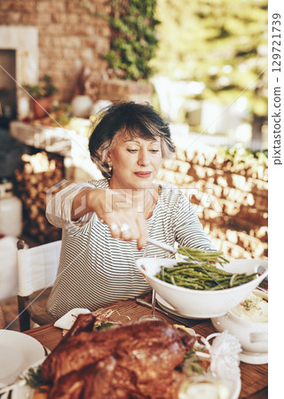 Dinner, dish and senior woman with food at an outdoor dinner, party or event in the garden. Eating, lunch and elderly lady serving vegetables with roast meat at a outside dining table at her home. Dinner, dish and senior woman with food at an outdoor dinner, party or event in the garden. Eating, lunch and elderly lady serving vegetables with roast meat at a outside dining table at her home. 129721739