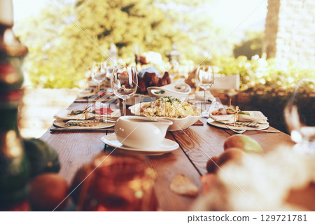 Food, celebration and dinner party in a garden for fine dining, nutrition and table setting. Lunch, celebration and tradition on a patio with a prepared dinner on a table in the backyard of a house 129721781