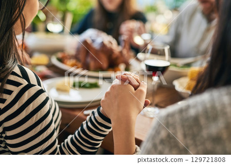 Food, praying and family holding hands for prayer with parents and children gathering at a dinner table at home. God, worship and grateful people with gratitude enjoy a thanksgiving meal with turkey 129721808