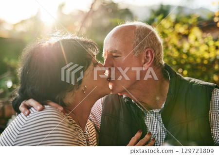 Kiss, love and senior couple in nature for love, date and affection during retirement holiday. Happy, care and interracial man and woman kissing with an embrace and smile in a park or garden Kiss, love and senior couple in nature for love, date and affection during retirement holiday. Happy, care and interracial man and woman kissing with an embrace and smile in a park or garden 129721809