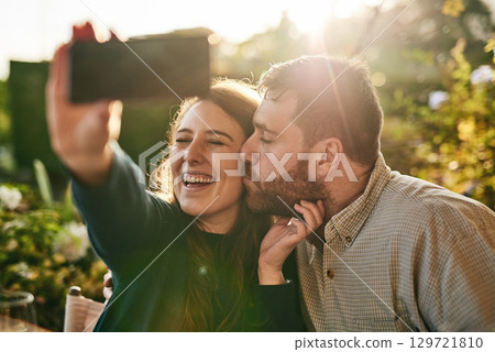 Love, couple and selfie on a patio by happy people kiss, bond and relax at sunset together. Family, phone and man kissing woman for picture while sitting in a backyard, smile and loving at home Love, couple and selfie on a patio by happy people kiss, bond and relax at sunset together. Family, phone and man kissing woman for picture while sitting in a backyard, smile and loving at home 129721810