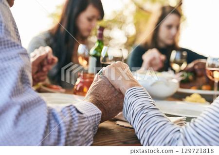 Family, prayer and lunch for thanksgiving, celebration or party in garden, backyard or outdoor restaurant. Holding hands, mindfulness and gratitude for worship, god and praying with food on table 129721818