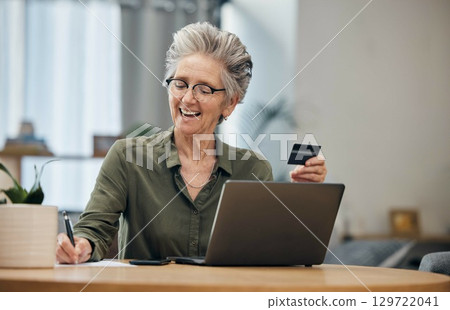 Laptop, credit card and senior woman paying her bills, debt or mortgage with online banking. Elderly lady planning a financial investment or calculating her retirement finances on paper at her home. 129722041