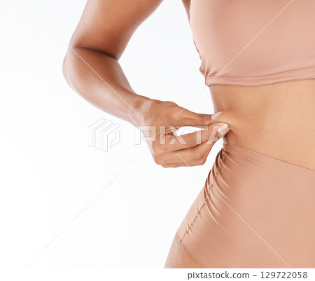 Woman, pinch stomach and weight loss in studio for wellness, health and care for body by white background. Young model, girl and hands on abdomen skin for tummy tuck, liposuction and cosmetic surgery 129722058