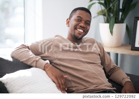 Relax, smile and portrait of black man on sofa at home in city apartment. Happy, healthy and proud man and leader in business from South Africa smiling and relaxing alone on couch in living room. Relax, smile and portrait of black man on sofa at home in city apartment. Happy, healthy and proud man and leader in business from South Africa smiling and relaxing alone on couch in living room. 129722092