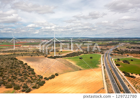 Wind turbines on open fields next to highway 129722780