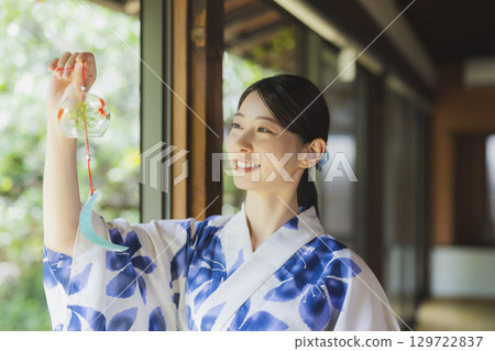 一個穿著浴衣的女人在門廊上拿著風鈴 一個穿著浴衣的女人在門廊上拿著風鈴 129722837