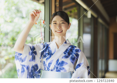 一個穿著浴衣的女人在門廊上拿著風鈴 129722840